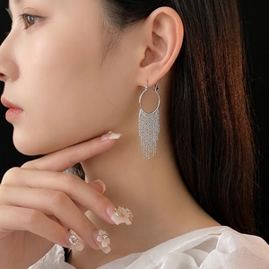 Boucles d'oreilles créoles argentées avec de longues glands en cascade sur un modèle