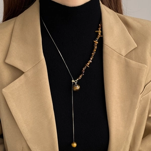 Detail of tiger eye stone pendant necklace with fringe chain on a female model