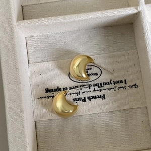 Macro shot of minimalist gold crescent earrings with a polished mirror finish detail