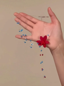 Detail der roten Blumenkette mit blauen Perlen an einem transparenten Nylonband