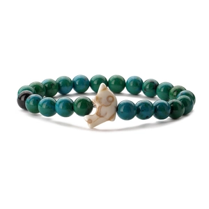 Detail of beaded bracelet with green turquoise beads and a white dolphin charm