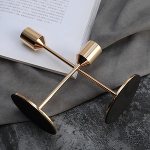 Elegantes Paar goldene Metall-Kerzenhalter mit schlanken Stielen auf dunklem Hintergrund