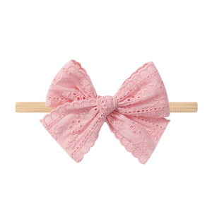 Détail d'un bandeau rose en dentelle ajourée sur ruban élastique en nylon pour bébés