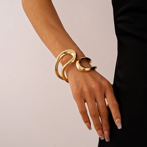 Bracciale scultoreo artistico color oro con finitura lucida indossato da una modella
