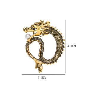 Detailed close-up of golden Chinese dragon brooch with white pearl and size dimensions