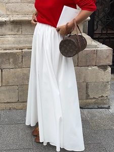 Detailed view of white high-waist pleated maxi skirt with flowing A-line silhouette