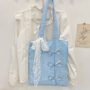 Detail of light blue sequin tote bag featuring elegant white lace edges and silver bows
