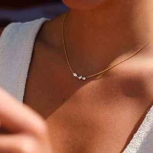 Close-up of minimalist gold necklace with marquise-cut zircon cluster on female collarbone