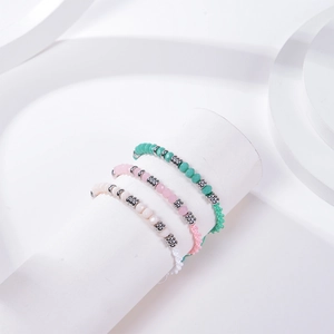 Three-piece set of woven Morse code bracelets with crystal beads on a white display stand
