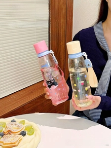 Detail of pink and yellow gradient cartoon straw bottles with woven carry handles