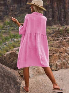 Pink short sleeve linen dress with pleated hem shown against a rocky mountain backdrop