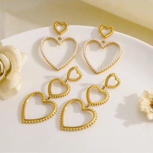 Detailed macro view of 18K gold heart earrings with delicate pearls and beaded edges