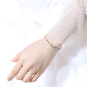 Dettaglio del bracciale intrecciato in argento con zirconi su piume bianche soffici