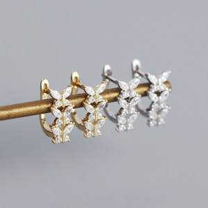 Close-up of gold and silver butterfly earrings with sparkling zircon inlay details