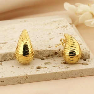 Polished gold-plated teardrop earrings with textured hollow grooves on stone tray