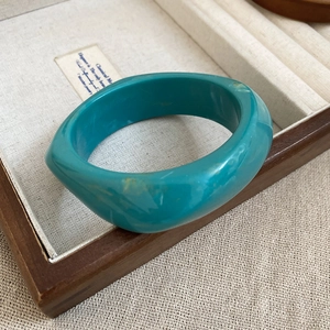 Detail view of a vintage gold-plated mother of pearl open bangle in a jewelry box