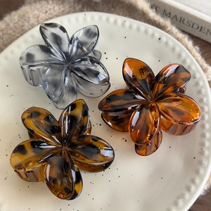 Detailed close-up of three leopard-print flower hair claws in amber and tortoiseshell resin