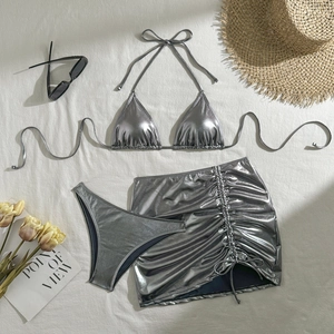 Detailed flat lay of silver metallic three-piece bikini set with drawstring skirt and sunglasses