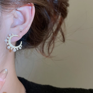 Nahaufnahme von Mondsichel-Ohrringen mit Zirkonia-Besatz und eleganten weißen Perlen