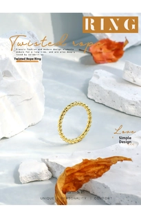 Artistic detail of gold twisted rope ring on white stone with autumn maple leaf