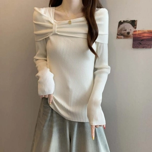 Detail of elegant white off-shoulder knit sweater with bow-style pleated neckline