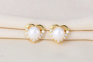 Detail of heart-shaped S925 silver pearl earrings with sparkling zircon accents