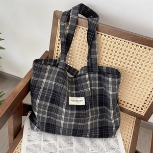 Close-up of the black and gray checkered canvas tote bag with a white woven label detail