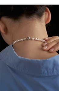 Detailed view of white pearl necklace with silver magnetic spherical clasp on neck
