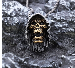 Macro shot of two-tone gothic grim reaper skull pendant on dark rock background