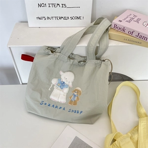 Close-up of light green canvas tote bag featuring cute animal embroidery and drawstring
