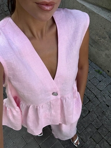 Detail eines rosa Leinentops mit V-Ausschnitt, strukturierter Stoff und Volant-Saum