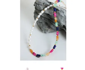 Macro detail of Baroque pearls and colorful natural stone beaded necklace on grey rock