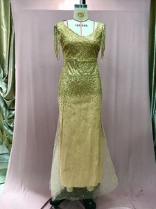 Dettaglio dell'abito da sera con paillettes dorate, scollo a V profondo e maniche a frange