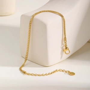 Close-up of 18K gold braided necklace with lobster clasp on white geometric stone