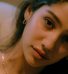 Close-up of a model wearing minimalist golden U-shaped earrings and a silver chain necklace