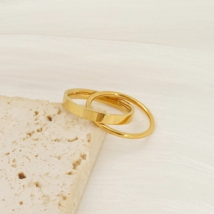 Double-layered gold titanium steel ring set displayed on a minimalist beige stone texture
