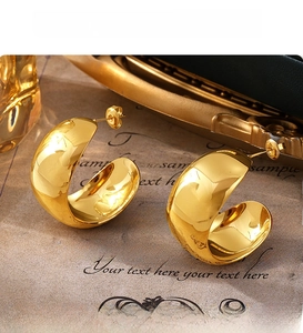Detail view of high-polished golden PVD plated C-shaped chunky earrings with studs