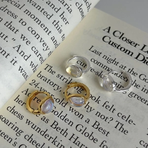 Macro detail of S925 silver and 18K gold earrings with iridescent stones on a book