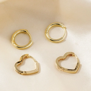 Detailed macro view of 18K gold heart and round hoop earrings with zircon on silk