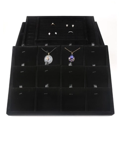 Detailed top view of stacked black velvet jewelry trays with necklace and ring compartments