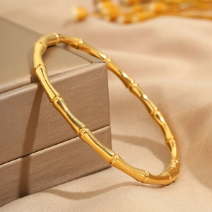 Dettaglio di un bracciale in acciaio inossidabile dorato a forma di bambù su scatola