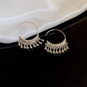 Macro shot of silver C-shaped metal earrings with multiple water drop tassel charms