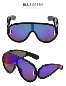 Detail of oversized shield sunglasses with blue-green gradient lenses and gold rivets