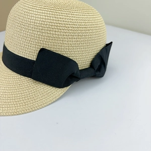 Detail of summer straw hat with fine weaving and a large black ribbon bow on the side