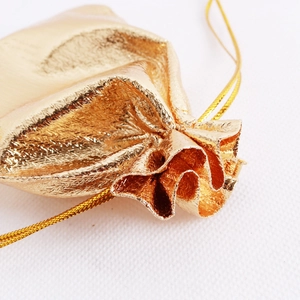 Macro detail of golden drawstring jewelry pouch showing metallic fabric texture