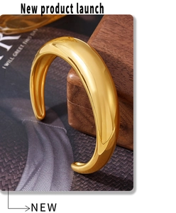 Macro shot of 18K gold plated cuff bracelet with polished mirror finish on wood