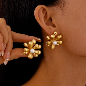 Détail de la boucle d'oreille fleur dorée avec perle blanche portée sur l'oreille