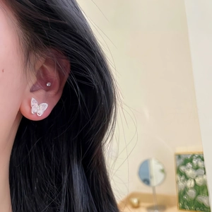 Elegant silver butterfly stud earrings with sparkling zircons worn on earlobe