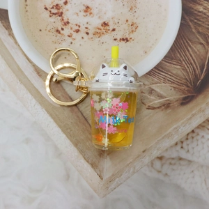 Detail of milk tea cup keychain with liquid glitter, cat icon, and sakura floral prints