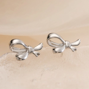 Boucles d'oreilles nœud en argent poli avec finition brillante sur fond texturé